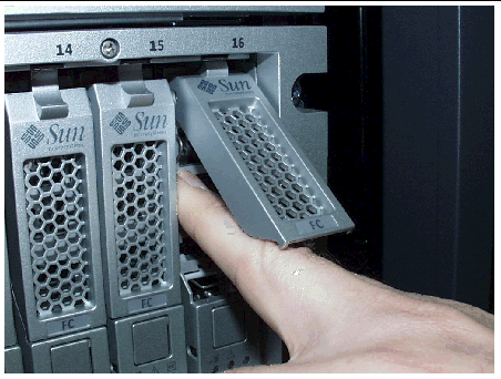 Figure shows the wrong way to insert the drive. The user is sticking a finger in the drive bay to seat the drive instead of pushing on the drive enclosure.